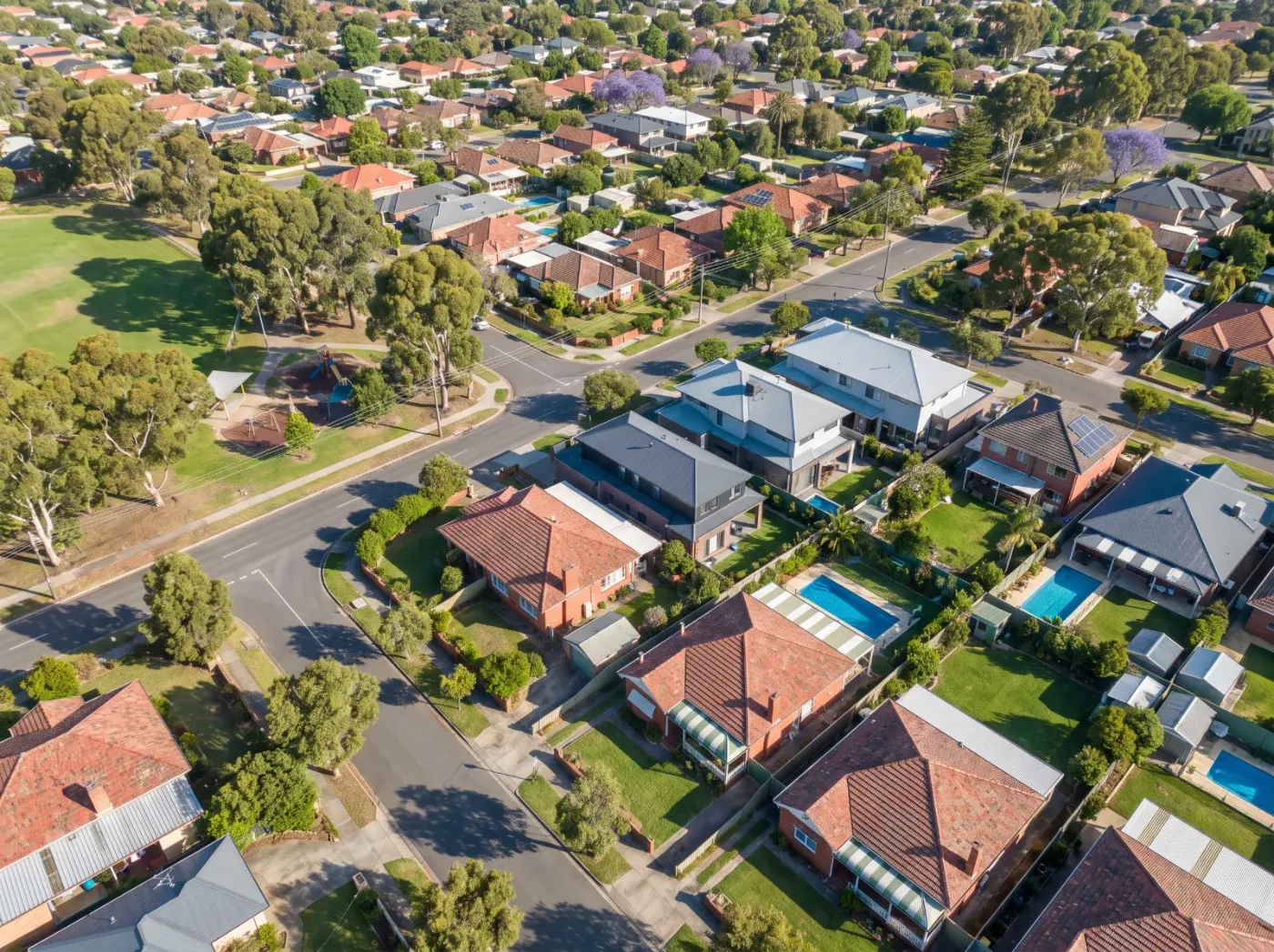Aerial view of an established Australian suburb with mixed rooflines, parks and mature tree canopy